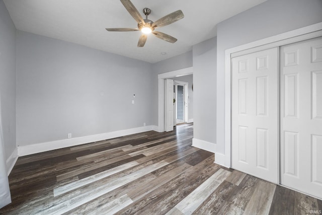 unfurnished bedroom with a closet, wood finished floors, a ceiling fan, and baseboards