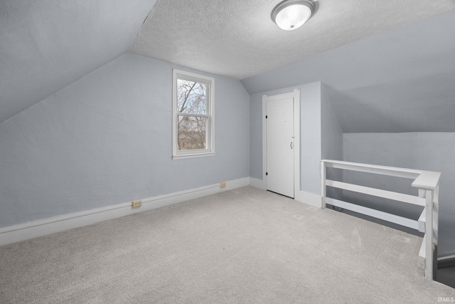 bonus room featuring lofted ceiling, carpet, a textured ceiling, and baseboards