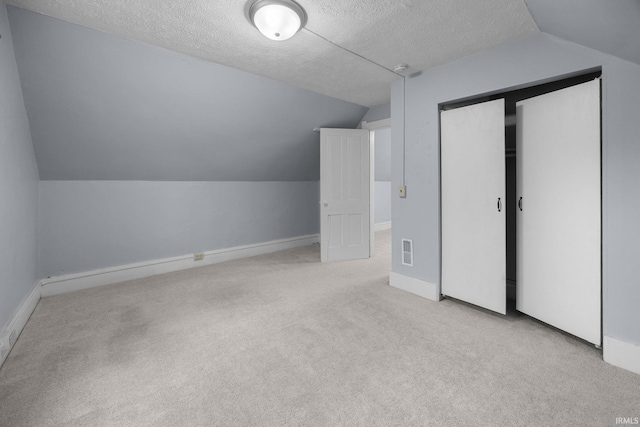 additional living space featuring visible vents, carpet flooring, vaulted ceiling, a textured ceiling, and baseboards