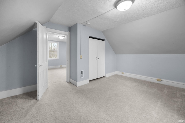 additional living space with carpet, a textured ceiling, and baseboards