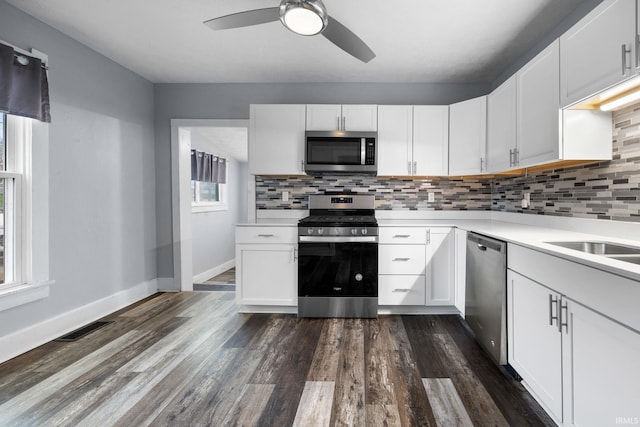 kitchen featuring stainless steel appliances, dark wood-style flooring, light countertops, and white cabinetry