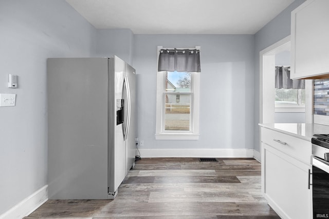 kitchen with baseboards, white cabinetry, stainless steel fridge with ice dispenser, and wood finished floors