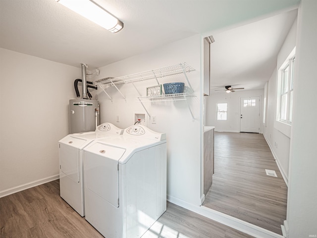 laundry area with baseboards, ceiling fan, washer and dryer, light wood-type flooring, and water heater