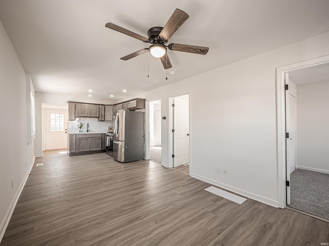 unfurnished living room featuring recessed lighting, a sink, wood finished floors, a ceiling fan, and baseboards