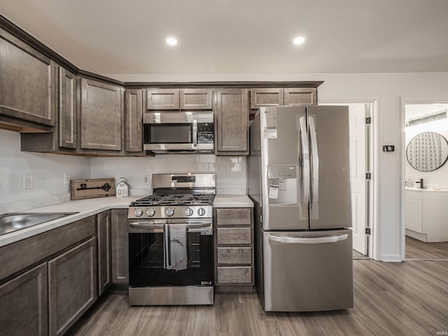 kitchen with appliances with stainless steel finishes, light countertops, and wood finished floors