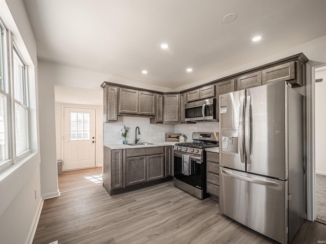 kitchen featuring light wood-style flooring, stainless steel appliances, a sink, and light countertops