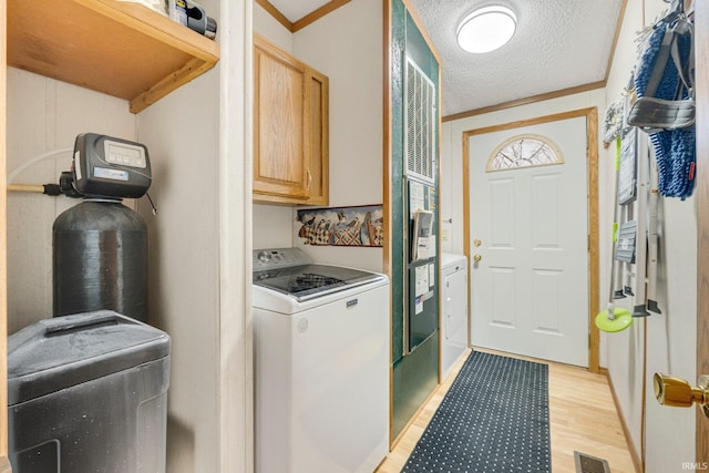 laundry room featuring a textured ceiling, visible vents, light wood finished floors, cabinet space, and washer / clothes dryer