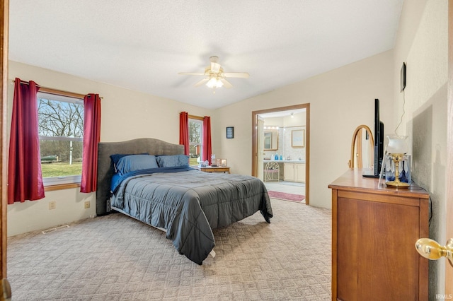 bedroom with ensuite bathroom, visible vents, vaulted ceiling, and light colored carpet