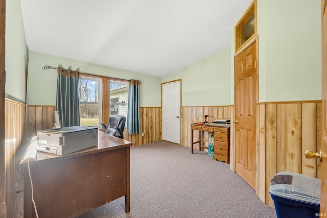 carpeted office featuring lofted ceiling, a wainscoted wall, and wood walls