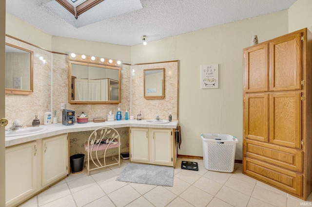 full bath featuring a textured ceiling, a skylight, vanity, and tile patterned floors