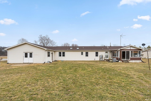 rear view of property featuring cooling unit, a sunroom, and a yard