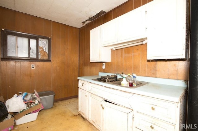 kitchen with light countertops, wood walls, and a sink