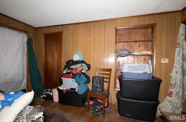 misc room with a textured ceiling, wood walls, wood finished floors, and crown molding