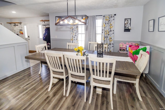 dining space with wood finished floors and wainscoting