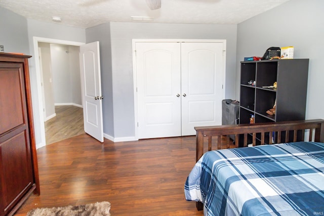 bedroom with a closet, a textured ceiling, baseboards, and wood finished floors