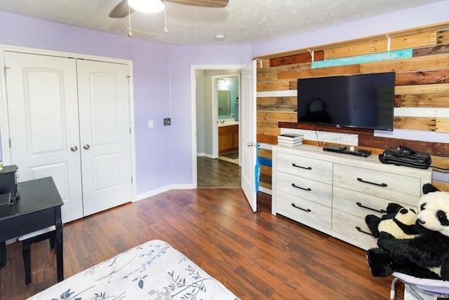 bedroom featuring a textured ceiling, ceiling fan, dark wood-style flooring, baseboards, and a closet