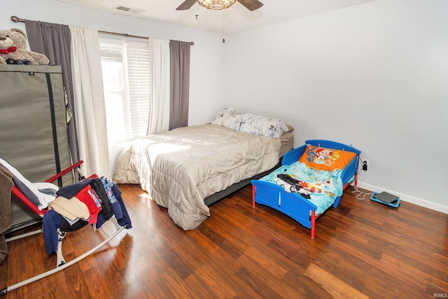 bedroom featuring a ceiling fan, wood finished floors, visible vents, and baseboards