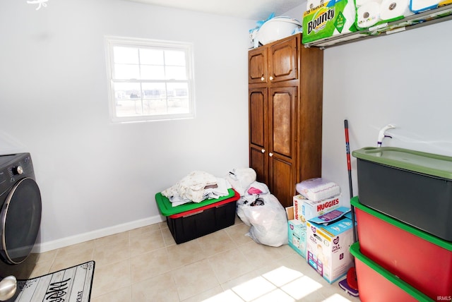 clothes washing area featuring washer / dryer, baseboards, cabinet space, and light tile patterned flooring