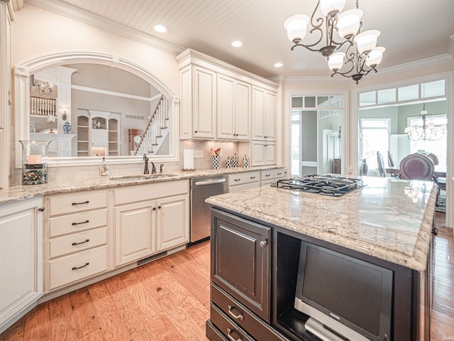 kitchen featuring light wood-style flooring, ornamental molding, an inviting chandelier, stainless steel appliances, and a sink