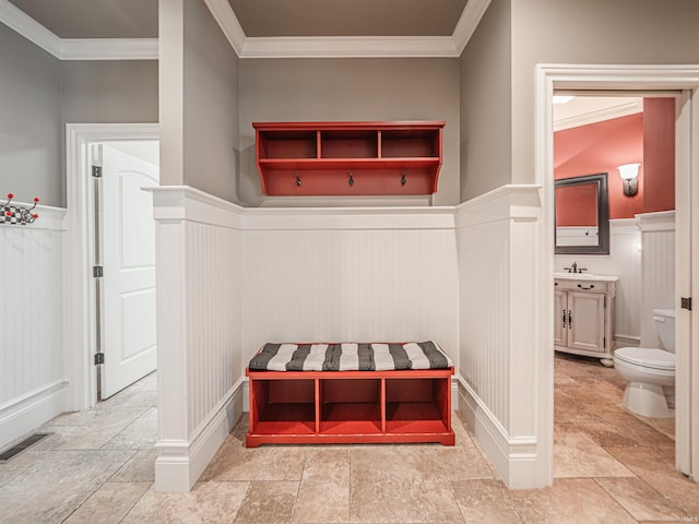 mudroom with crown molding, wainscoting, a sink, and visible vents