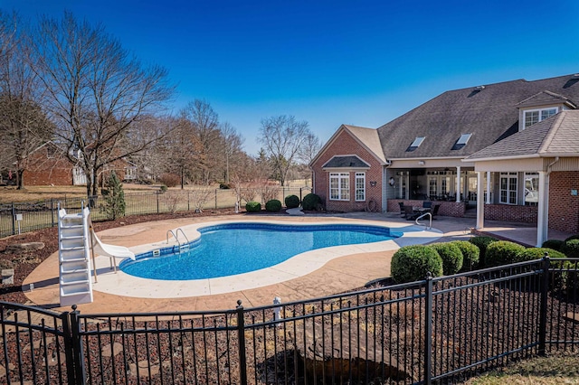 view of swimming pool featuring a fenced in pool, a water slide, a fenced backyard, and a patio