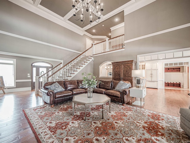 living area with a chandelier, arched walkways, stairs, ornamental molding, and hardwood / wood-style floors