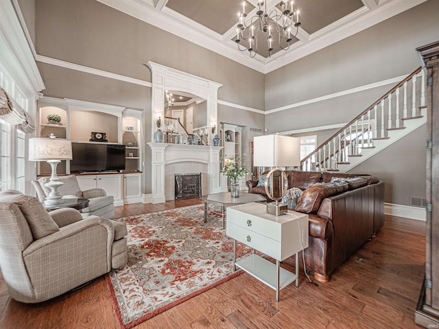 living room with stairway, a fireplace, a chandelier, and wood finished floors