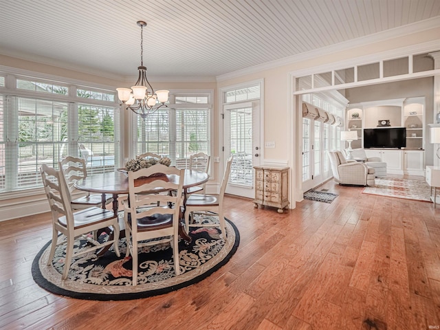 dining area with ornamental molding, a chandelier, plenty of natural light, and light wood finished floors