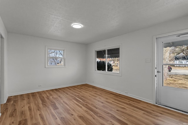 empty room featuring a textured ceiling, baseboards, and wood finished floors