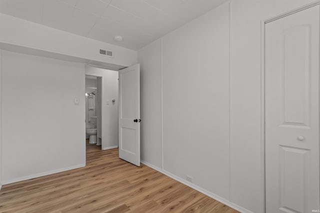 empty room featuring light wood-type flooring, baseboards, and visible vents