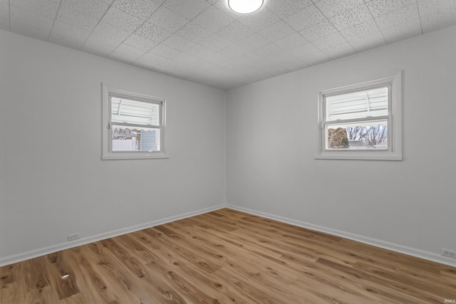 empty room with light wood-style floors, baseboards, and a wealth of natural light