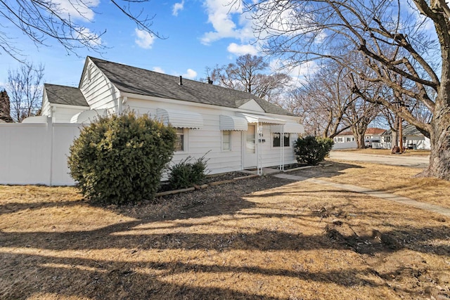 back of house featuring roof with shingles and fence