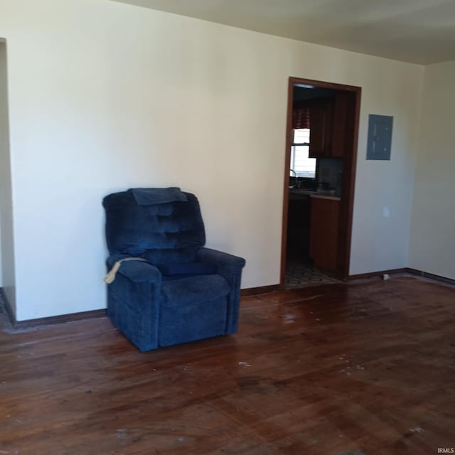 sitting room featuring dark wood-style flooring, electric panel, and baseboards