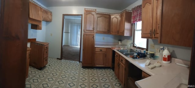 kitchen featuring brown cabinetry, light countertops, and a sink