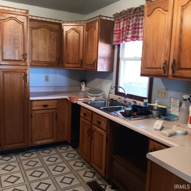 kitchen with light countertops, light floors, a sink, and brown cabinetry