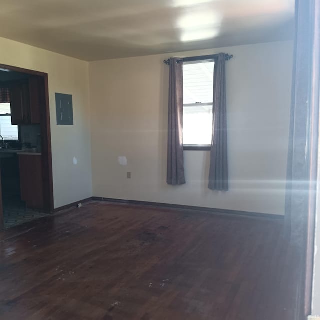 unfurnished room featuring electric panel, baseboards, and dark wood-type flooring