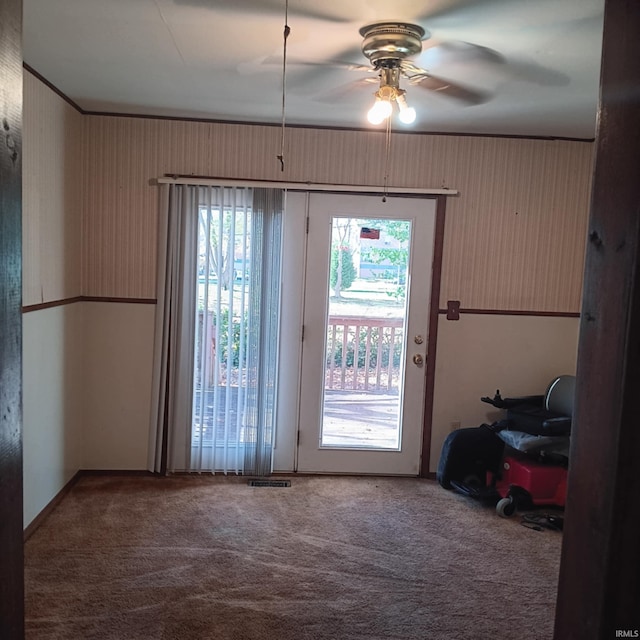 entryway with visible vents, carpet flooring, and a ceiling fan