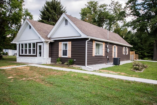 view of front of home with central AC unit, a front lawn, and roof with shingles