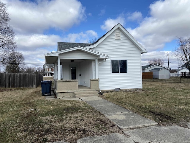 bungalow with covered porch, roof with shingles, fence, and a front yard