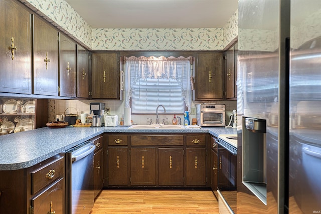 kitchen with light wood-style floors, wallpapered walls, appliances with stainless steel finishes, and a sink