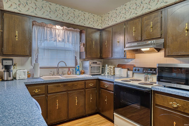 kitchen featuring a toaster, backsplash, a sink, range with electric cooktop, and under cabinet range hood