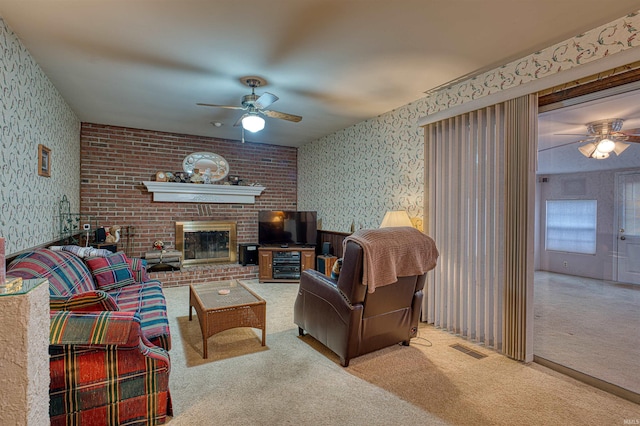 carpeted living area with ceiling fan, visible vents, a fireplace, and wallpapered walls