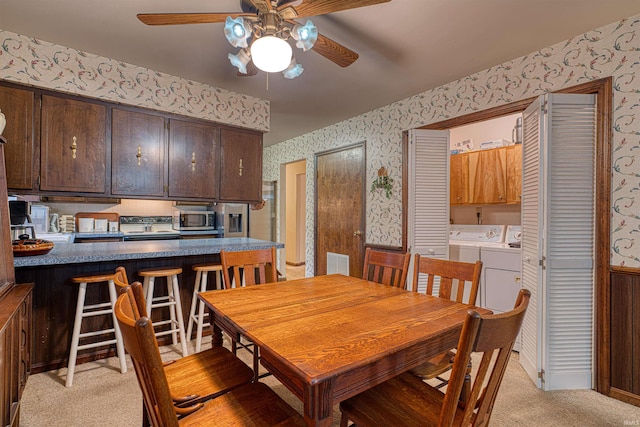 dining room featuring light carpet, wallpapered walls, visible vents, a wainscoted wall, and washer and dryer