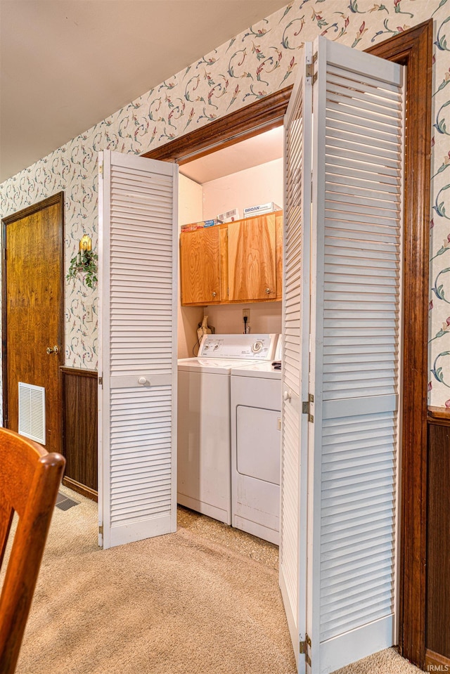 laundry area featuring light colored carpet, cabinet space, visible vents, independent washer and dryer, and wallpapered walls