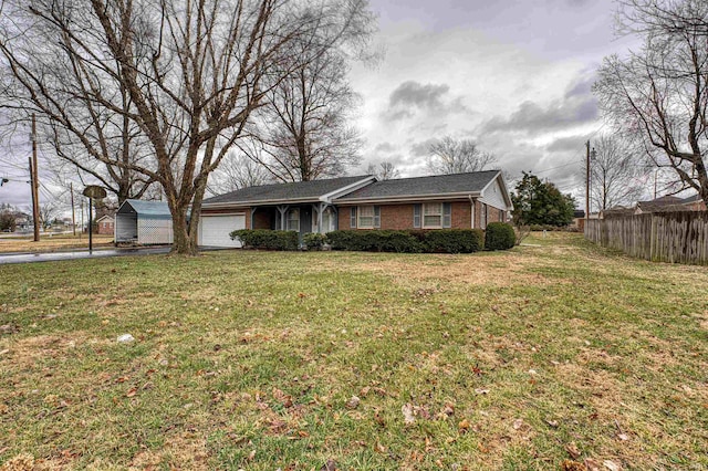 single story home with aphalt driveway, a garage, brick siding, fence, and a front yard