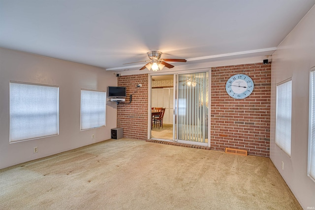 spare room featuring carpet floors, brick wall, visible vents, and a ceiling fan