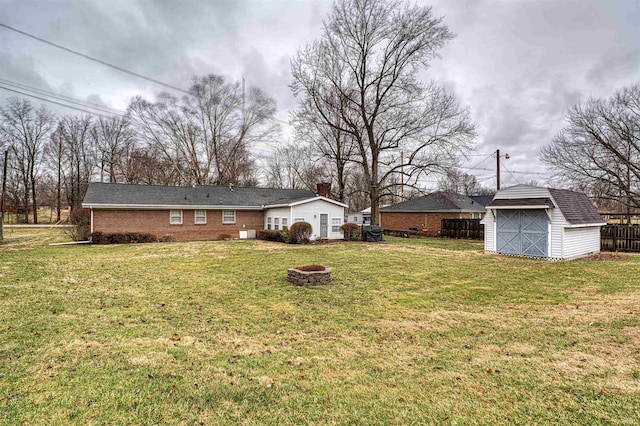 view of yard featuring an outdoor structure, an outdoor fire pit, fence, and a storage shed