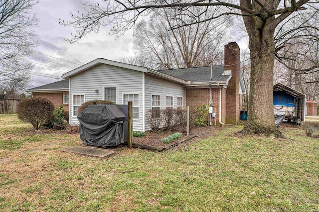 back of house with brick siding, fence, roof with shingles, a lawn, and a chimney