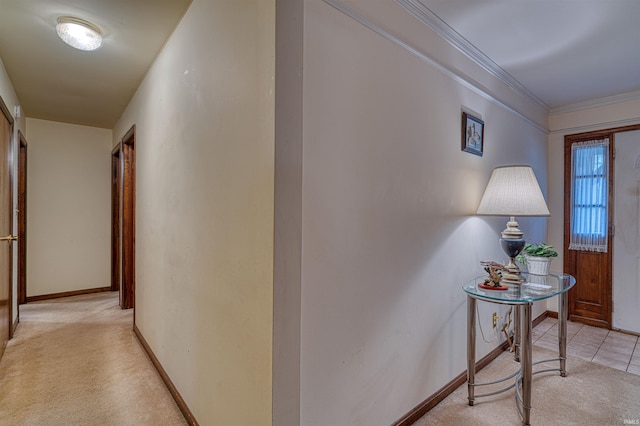 corridor with ornamental molding, light carpet, baseboards, and light tile patterned floors