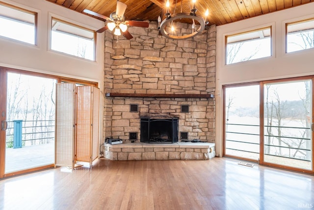 unfurnished living room featuring a fireplace, visible vents, a towering ceiling, wood finished floors, and wooden ceiling